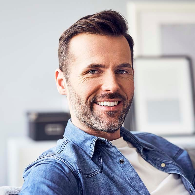 portrait-of-smiling-man-sitting-on-sofa-ADHXL78.jpg